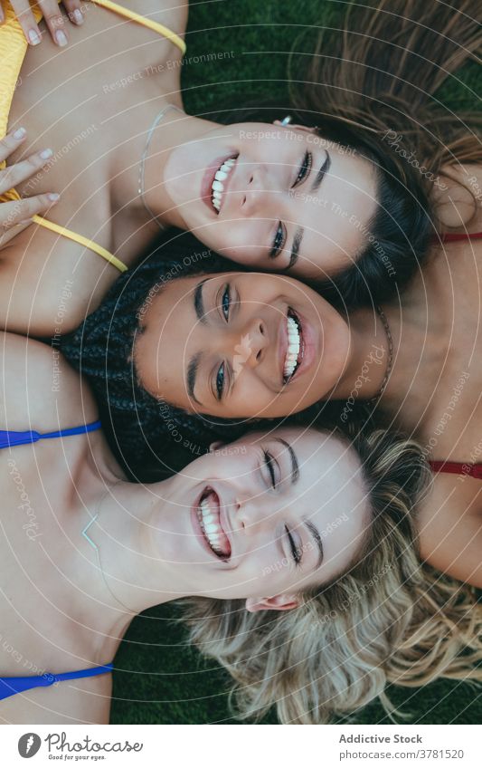 Happy multiracial women lying together on grass face to face friendship carefree young friendly freedom multiethnic diverse african american black weekend lawn