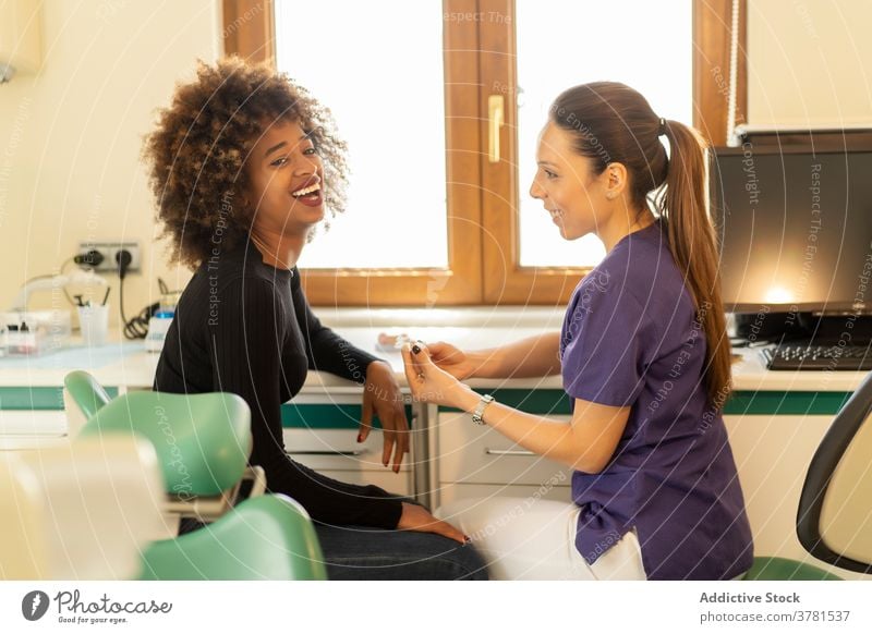 Black woman talking with dentist patient reception teeth implant dental clinic professional counter nurse doctor female multi ethnic multiracial diversity