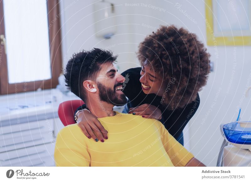 Cheerful black woman supporting boyfriend in dentist office couple cheerful comforting visit together clinic looking at each other young patient medicine happy