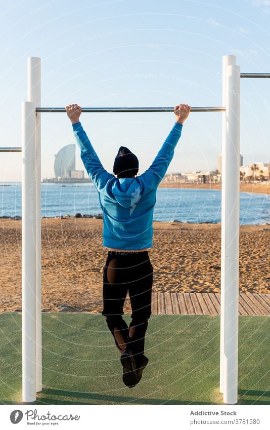 Strong man exercising on bar near sea training pull up beach workout fitness exercise sporty ocean active male healthy strong sports ground effort equipment