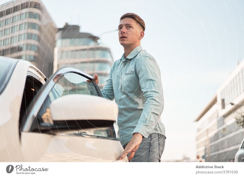 Serious man getting in in car in city automobile get in parked road driver male modern urban handsome town vehicle transport street parking cityscape automotive