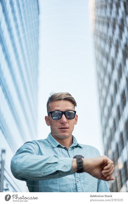 Stylish male entrepreneur checking time on wristwatch time management businessman downtown wait accuracy style street city busy urban contemporary job confident