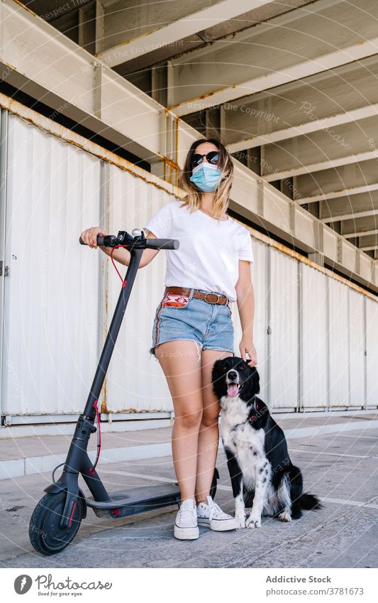 Young woman with electric scooter and dog mask active rider pet friend together companion female teen young teenage lifestyle transport vehicle friendship