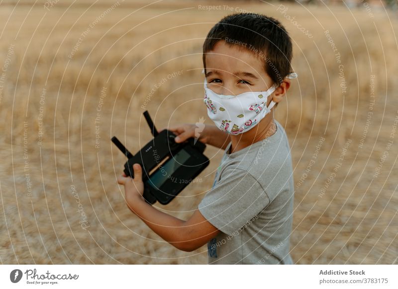 Little kid operating drone in field control remote operate using mask boy play little asian ethnic male child childhood game entertain device uav handset pilot