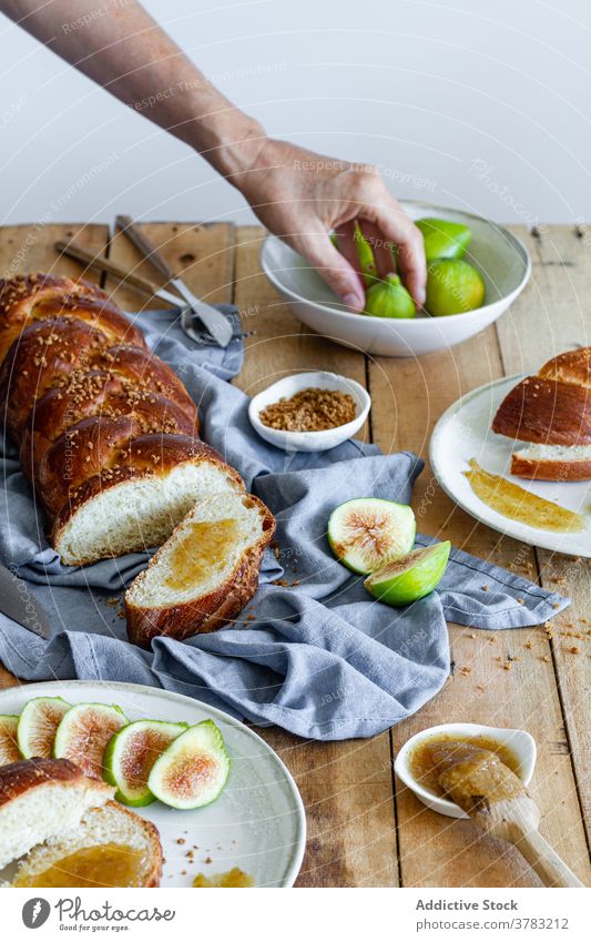 Anonymous woman holding fig near bread with jam braid sweet breakfast serve piece hand baked loaf food fruit eat slice snack handmade gastronomy fresh tasty