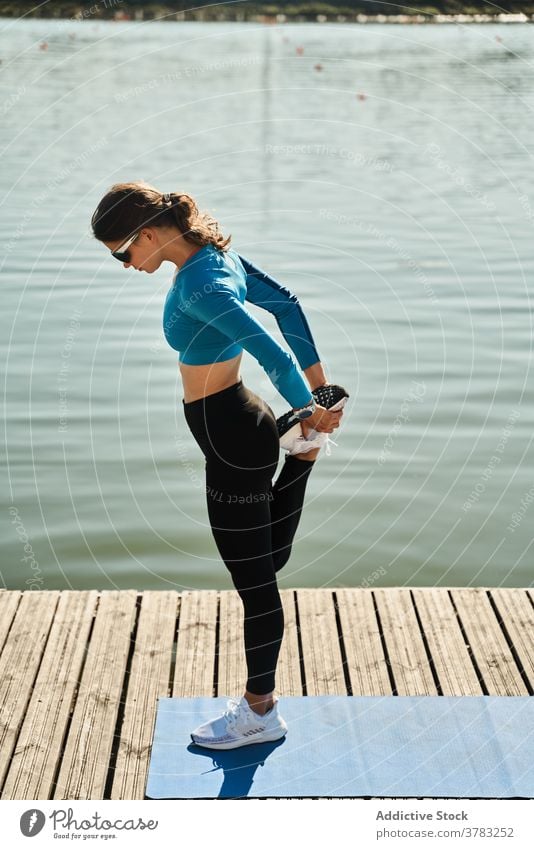 Slim woman in sportswear exercising on pier training stretch leg fit slim workout fitness exercise embankment sporty active female warm up healthy flexible