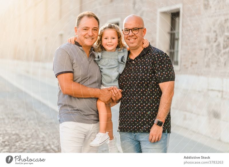 Delighted LGBT family walking on street lgbt together father men gay couple child entertain city passage weekend summer kid happy joy cheerful cute girl