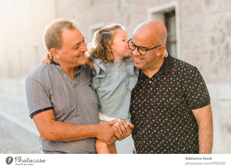 Delighted LGBT family walking on street lgbt together father men gay couple child entertain city passage weekend summer kid happy joy cheerful cute girl