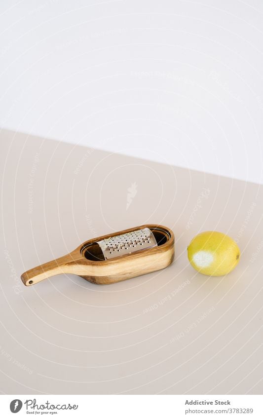 Grater and lemon on table in studio grater sharp citrus zest tasty vitamin natural organic sour rasp wooden fruit fresh whole food composition minimal simple