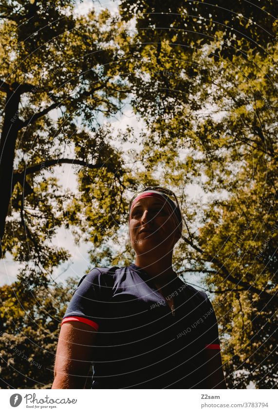 Young sportswoman in the forest Young woman Forest Sports Jersey sunglasses Green trees Bushes Pride Self-confident salubriously fortunate naturally