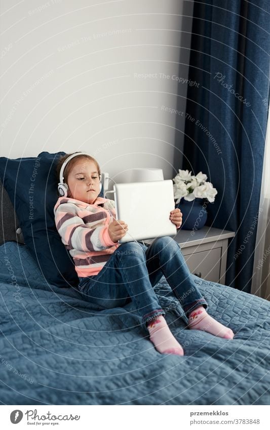 Little girl preschooler learning online solving puzzles playing educational games on tablet at home attention bed bedroom caucasian child childhood computer