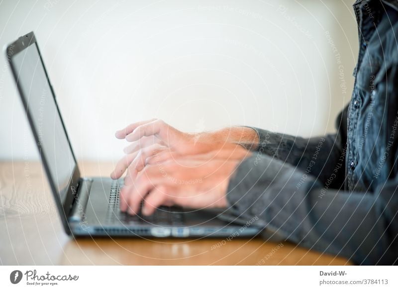 Man types with fast fingers on laptop Typing swift Keyboard Hurry time pressure Stress Speed Movement motion blur Business labour home office hands