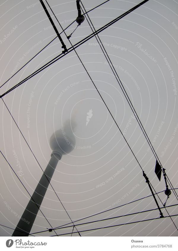 Berlin television tower in fog with overhead lines in the foreground Television tower Fog Haze Overhead line Tram Gray Clouds in the sky Covered Alexanderplatz