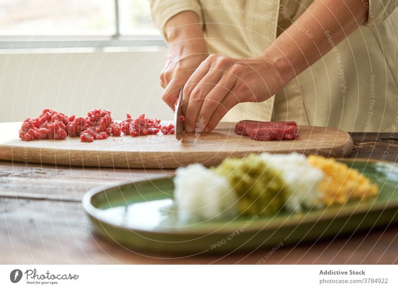 Crop woman cutting meat in kitchen beef cook steak tartare housewife prepare dinner dish cutting board chopping board fresh wooden delicious cuisine knife