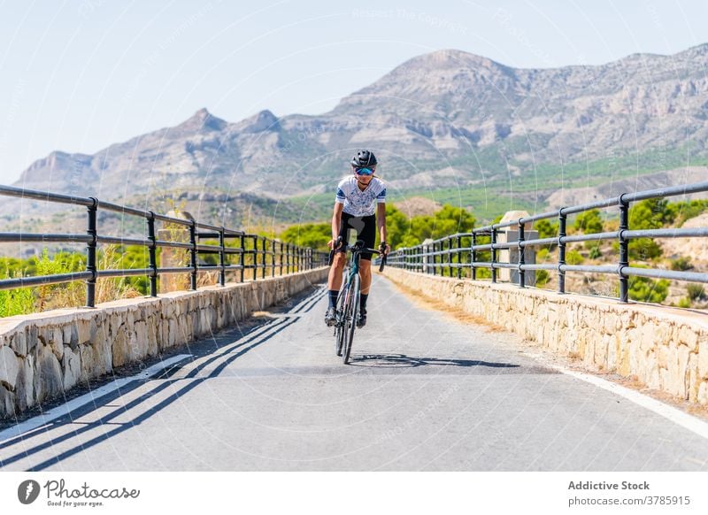 Cyclist riding bike on rural road in highlands cyclist ride mountain bicycle active sport route workout nature woman lifestyle activity healthy summer adventure