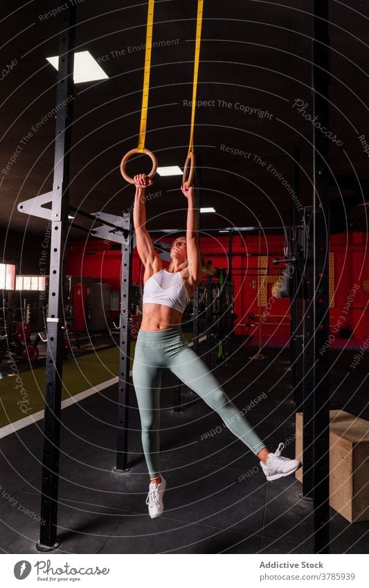 Enduring sportswoman doing exercises on gymnastic rings training abs balance strong effort abdomen calisthenics female fitness center workout power slim