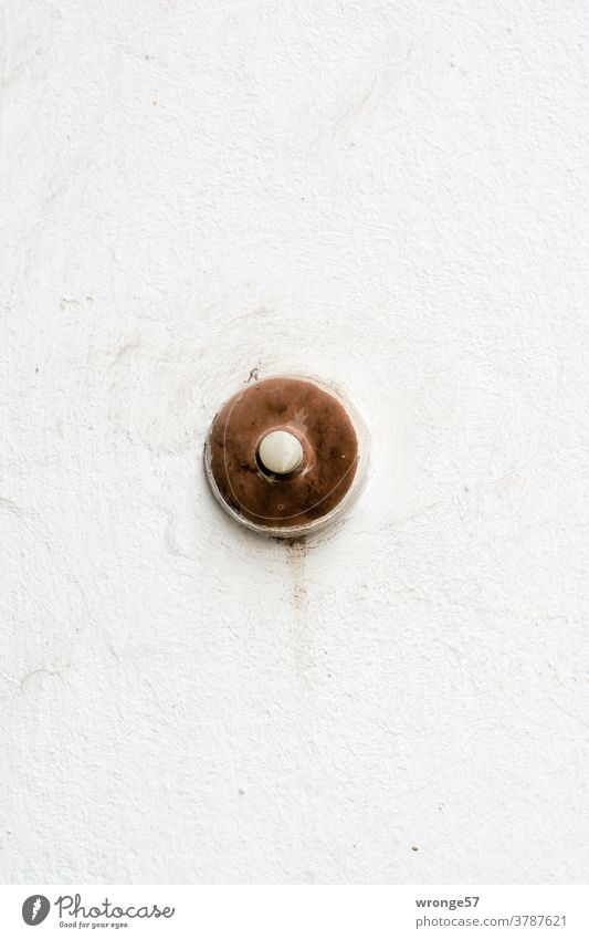Old aging bell button on a light grey house wall Bell Round Brown Colour photo Wall (building) Exterior shot House (Residential Structure) Facade Day Deserted