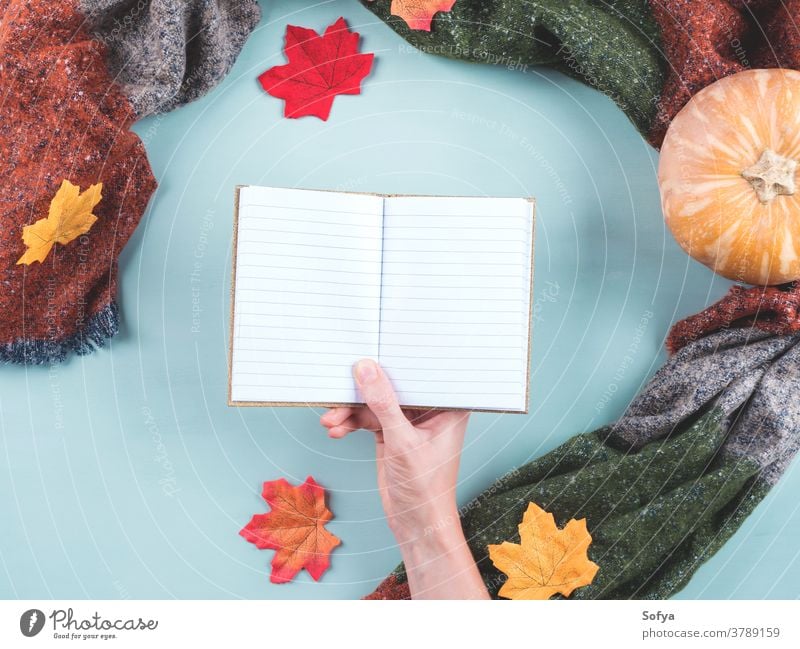 Empty notebook in female hand in scarf frame fall autumn holding diary blank empty page planner notepad open write journal pumpkin cozy thanksgiving halloween