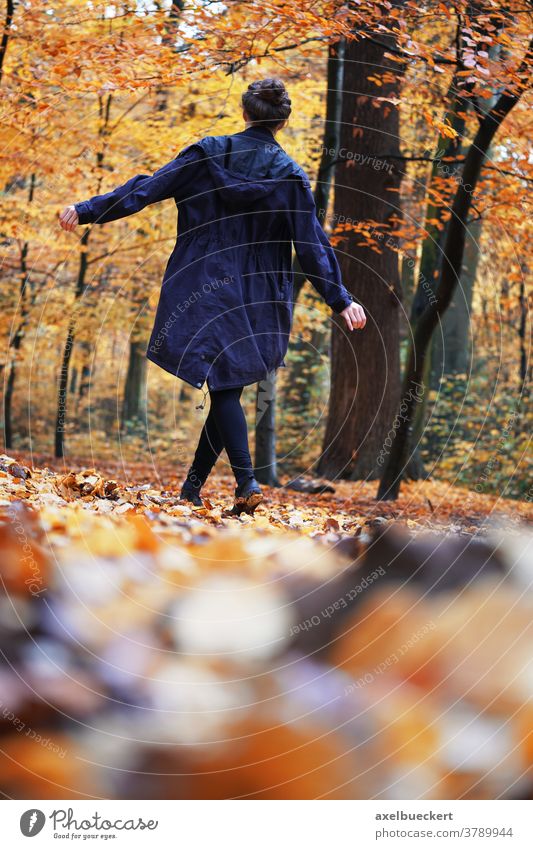 rear view of woman enjoying autumn walk in forest nature outdoor fun happy girl walking away dancing young fall real authentic female person people beautiful