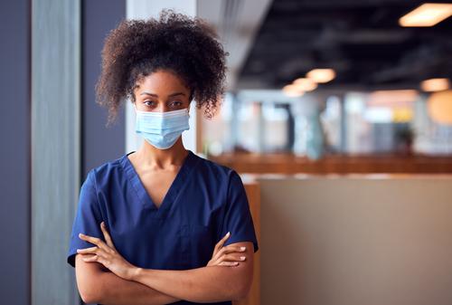 Female Doctor In Face Mask Wearing Scrubs Under Pressure In Busy Hospital During Health Pandemic doctor nurse scrubs key worker female woman wearing face mask