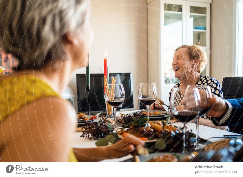 Laughing women interacting at table during Christmas dinner laughing food christmas alcohol friend smile celebrate festive flat red wine grape cheerful event