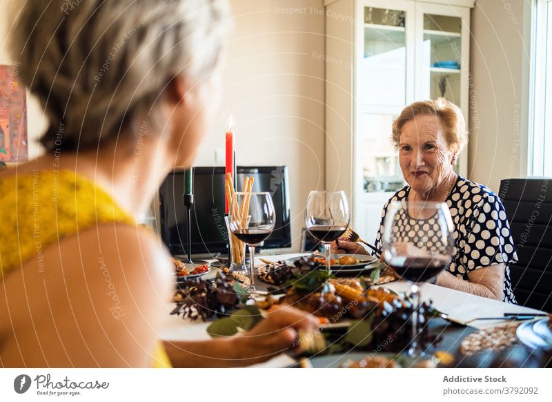 Smiling women interacting at table during Christmas dinner food alcohol friend smile celebrate christmas festive flat red wine grape cheerful event together