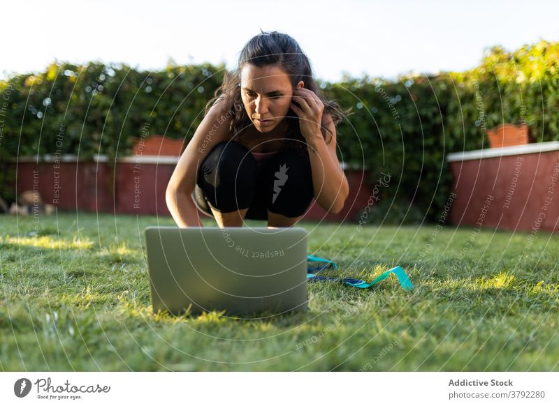 Sportswoman watching online tutorial during training workout choose pick laptop using sportswoman female backyard summer fitness browsing athlete healthy