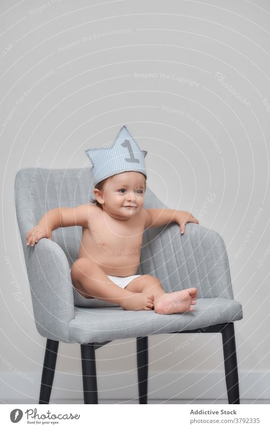 Cute boy in crown at home clap hand cheerful adorable child little stand toy armchair kid positive cute fun joy having fun childhood innocent happy glad