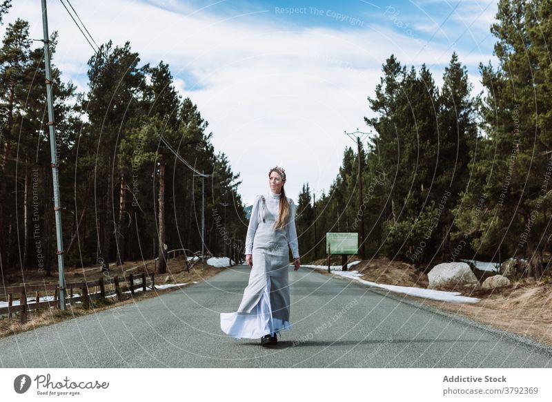 Calm woman walking along road in coniferous forest in spring serene route promenade charming dress environment stroll nature gorgeous grace harmony trendy alley