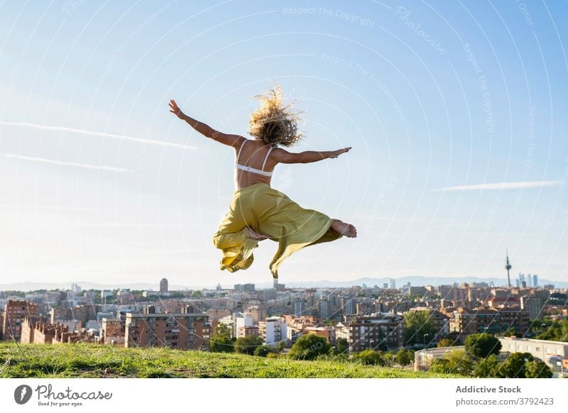 Faceless energetic woman jumping on city hill activity energy arms raised carefree delight excited leap hilltop vitality slim outstretch happy style joy harmony