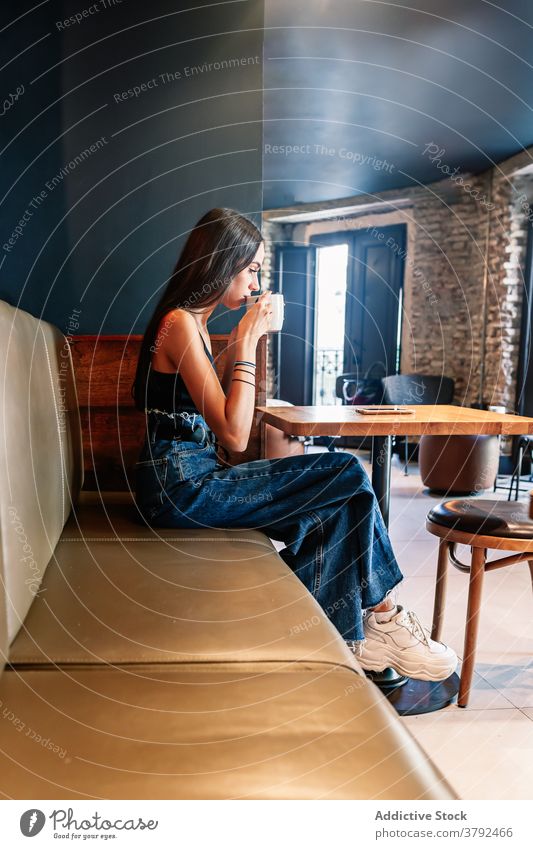 Stylish woman drinking coffee in cafe shop style brunette serene relax fashion chill rest table elegant outfit beverage cup hot drink comfort cozy calm female