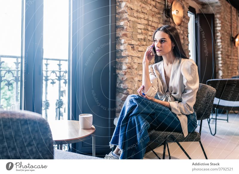 Woman drinking coffee near window while using smartphone woman style brunette serene relax fashion chill rest elegant outfit beverage cup hot drink comfort cozy