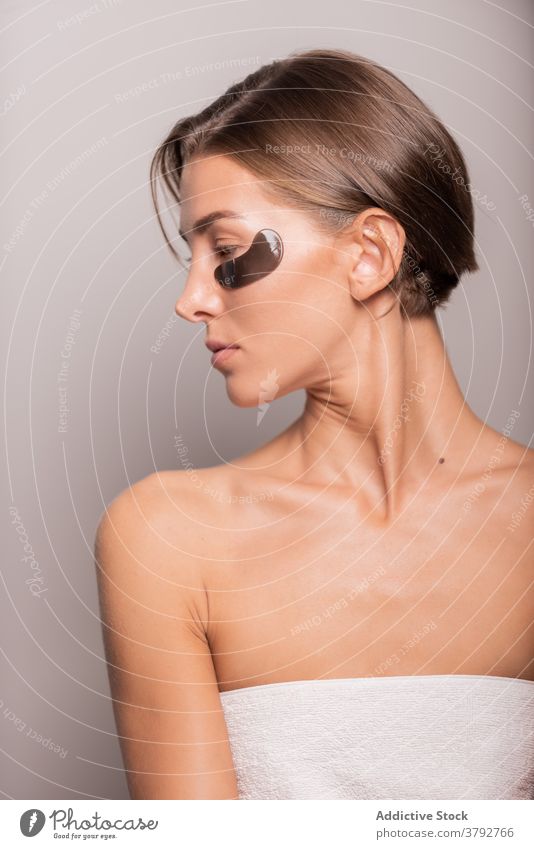 Serene woman doing daily routine treatment in studio eye patch skin care beauty black patch female natural cosmetology wellness perfect charming smooth