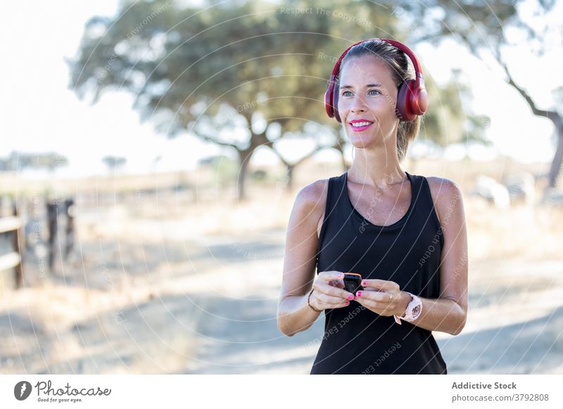 Woman using MP3 player and headphones in park woman gadget listen mp3 sound melody audio podcast music entertain song young concentrate focus headset modern
