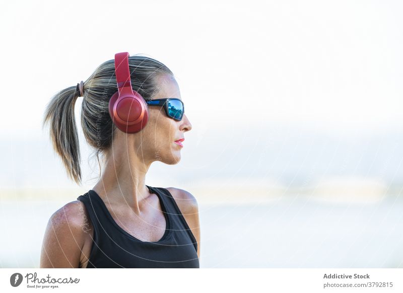 Woman with headphones before working out in park sportswoman listen fitness workout music slim vitality athlete activity training sporty activewear sportswear