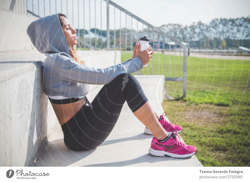 Portrait of beautiful sportswoman sunbathing activewear adult athletic girl runner exercise cardio fitness jogging lifestyle smartphone sportswear latin