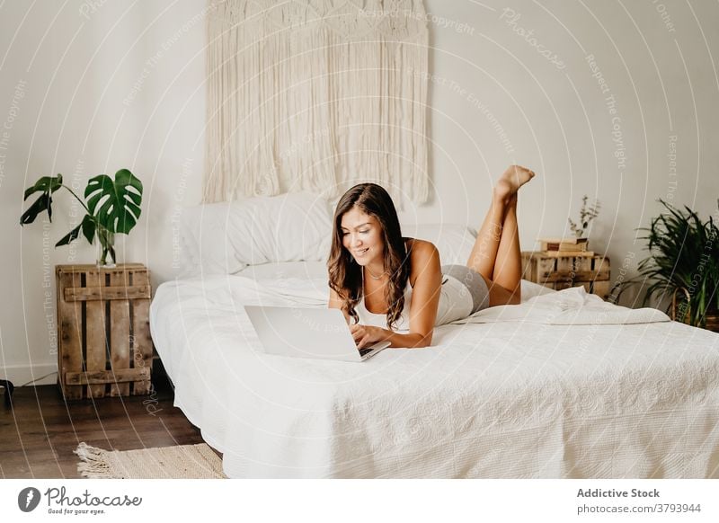 Joyful woman browsing laptop on bed morning using happy bedroom home cheerful young female device gadget internet cozy carefree chill student online delight