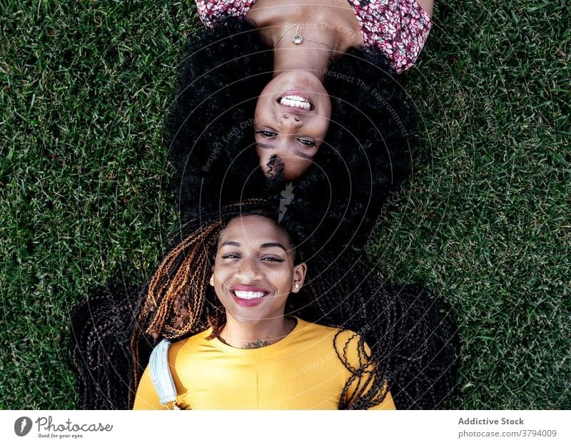Content black women on grass in park friendship lying content girlfriend together smile summer ethnic african american weekend carefree joy delight positive
