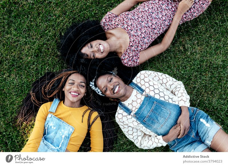 Positive diverse women lying on grass in park friendship positive together friendly bonding young multiethnic multiracial black african american green lawn