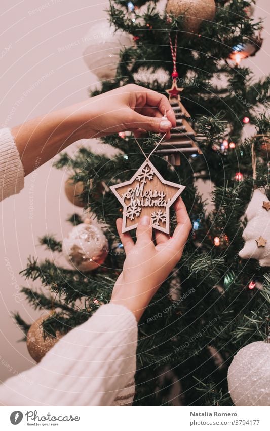 A person is decorating the Christmas tree. The person is hanging a Christmas star with a Christmas greeting. Close Up. christmas decorative celebration