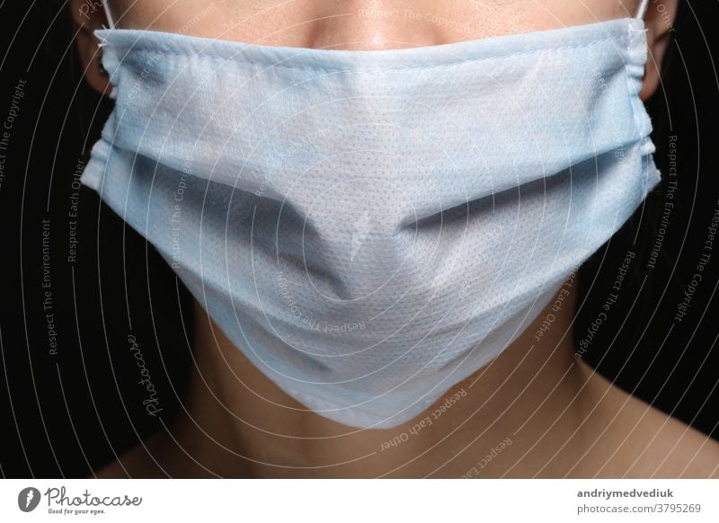 Young woman wearing face medical mask to prevent infection, illness or flu and 2019-nCoV. Black background. Protection against disease, coronavirus. portrait