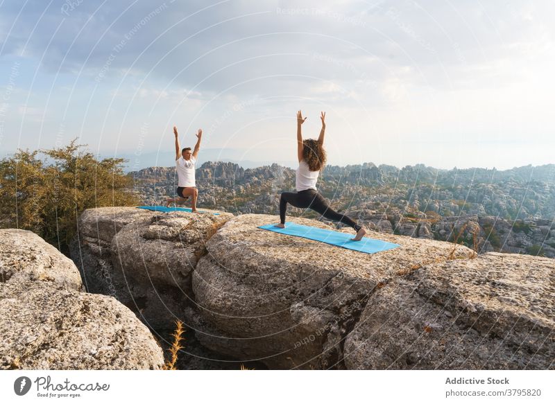 Couple standing in yoga asana on rock couple crescent lunge mountain nature practice together pose acro yoga position wellness lifestyle harmony balance