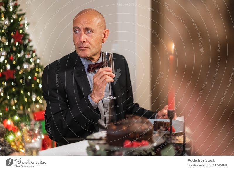 Elegant man at Christmas table at home christmas banquet champagne elegant holiday mature celebrate festive male serious party merry alcohol glass outfit drink