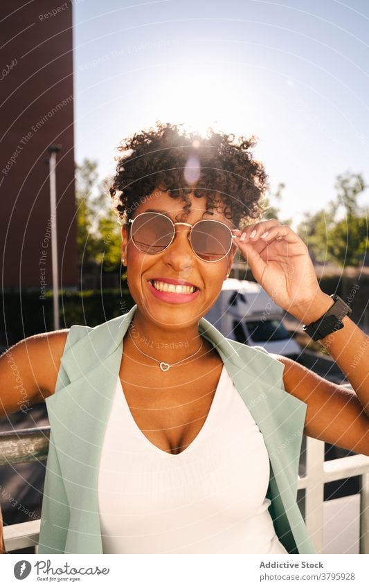 Stylish ethnic woman in sunglasses standing near fence style trendy happy summer afro smile cheerful young female african american black positive relax casual