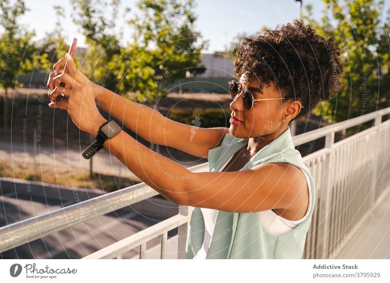 Stylish ethnic woman in sunglasses taking selfie near fence style trendy happy summer afro smile cheerful young female african american black positive relax