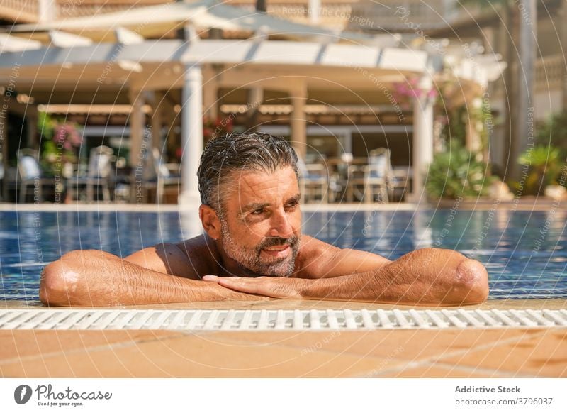 Relaxed man chilling in swimming pool in resort summer happy enjoy travel relax poolside vacation male beard ethnic adult handsome tropical holiday rest