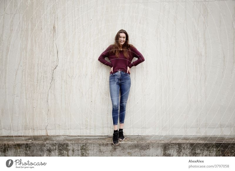 Portrait of a young woman standing on a wall in front of a concrete wall Woman Young woman 18-25 years warmly pretty Charming Slim Brunette long hairs Fresh