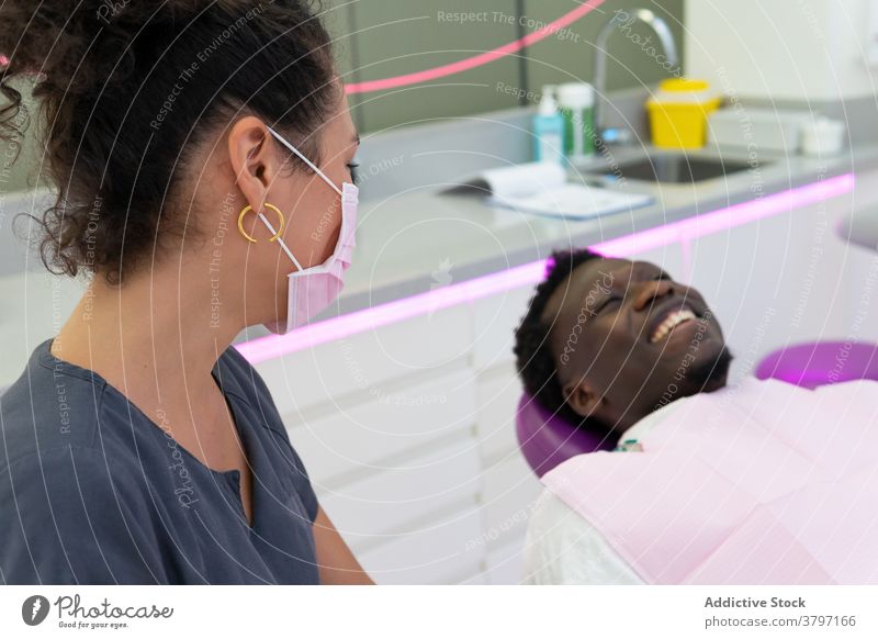 Smiling black dentist and patient in medical room doctor treat procedure dental dentistry stomatology ethnic african american mask cheerful professional