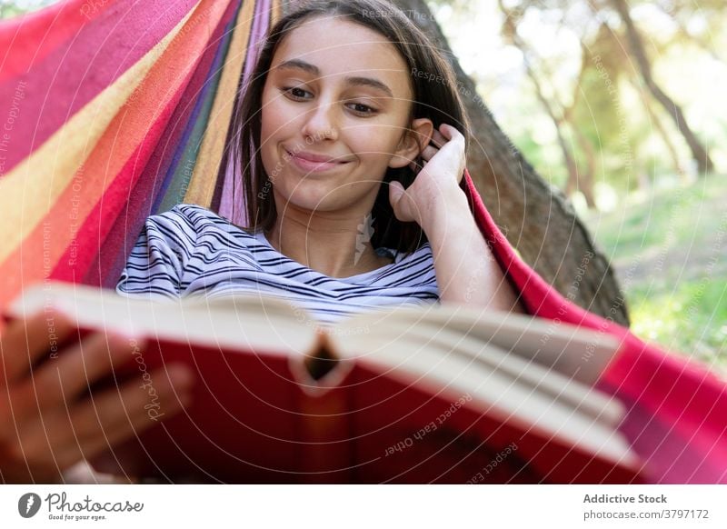 Relaxed woman reading book in hammock story enjoy summer lying park literature female interesting peaceful novel tranquil casual hobby nature recreation idyllic