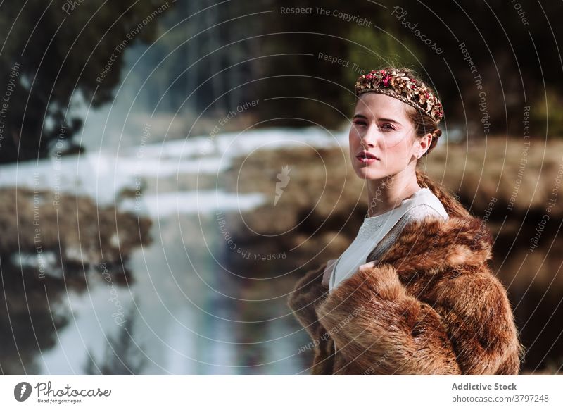 Elegant woman in fur wear and floral wreath standing in nature nordic tradition fashion style outfit feminine sensual dreamy wedding scandinavian charming